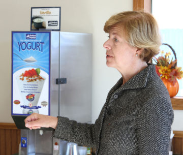 Senator Tammy Baldwin next to the perfect parfait yogurt dispenser at Westby Cooperative Creamery Cheese Store.