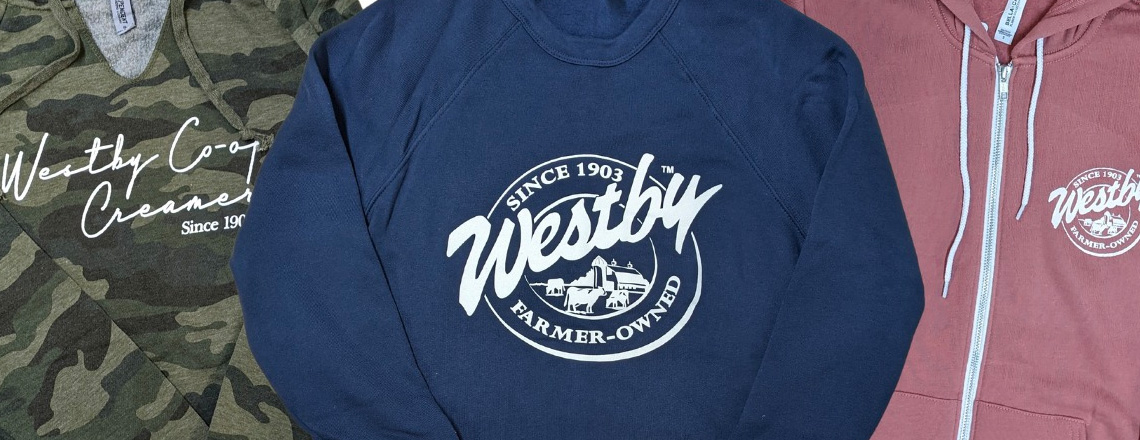 Close up of Westby Cooperative Creamery branded hoodies, sweatshirts, and t-shirts.