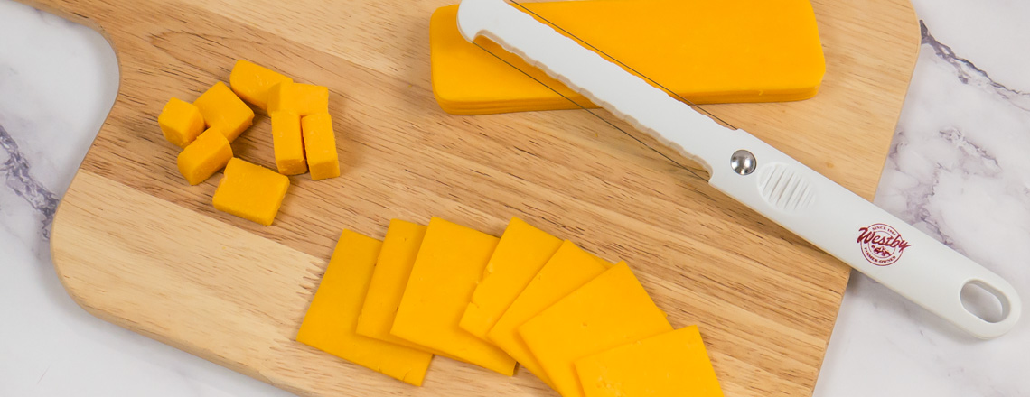 Westby Cooperative Creamery Medium Cheddar Cheese sliced and arranged on a cutting board.