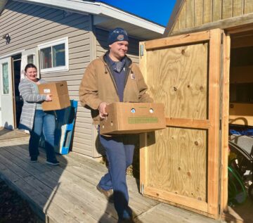 Westby Creamery employees carrying in boxes of donated items to Bethel Butikk