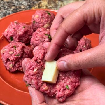 Close-up of a hand stuffing the meatballs with Westby Creamery string cheese.