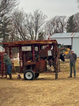 A Holstein cow getting her hooves trimmed by Tom while Carter Rogers gives her words of encouragement.