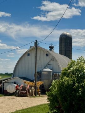 Carter Rogers standing next to a tractor outside of the barn of High Grove Farm.