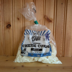 Bag of WW Homestead Dairy Cheddar Cheese Curds In Flavor Natural against a wooden background.